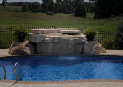 Backyard pool with a waterfall feature from a natural stone.