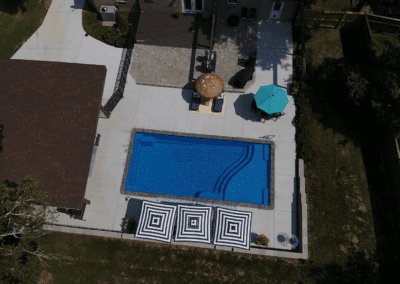 Rectangular pool with umbrellas and lounge chairs.